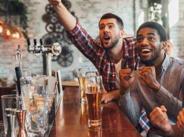 3 garçons dans un bar regardant du sport