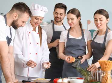 Personnes durant un cours de cuisine dispensé par un chef